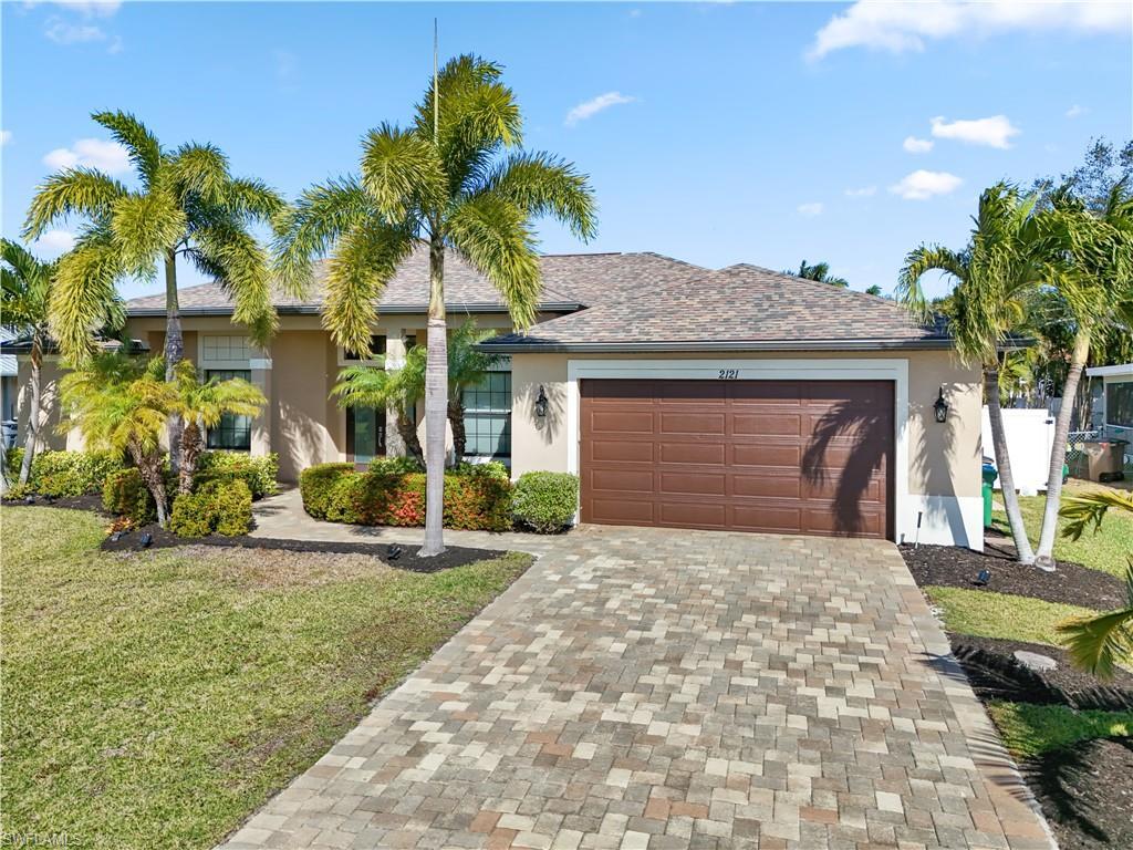 Image 2: Ranch-style house featuring decorative driveway, a front lawn, stucco siding, and an attached garage