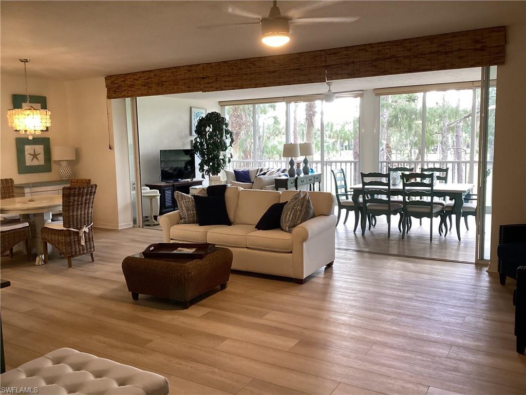 Image 2: Living room featuring light wood-type flooring, a chandelier, and a ceiling fan