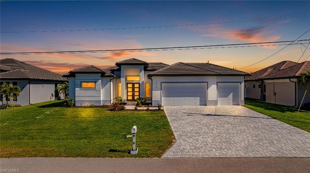 Image 3: Prairie-style home with a yard, a garage, a tile roof, and stucco siding