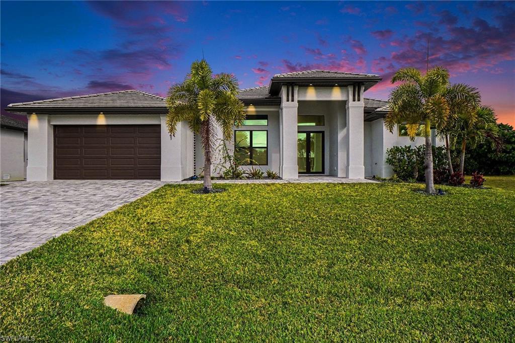 Image 1: Prairie-style house featuring a tile roof, decorative driveway, stucco siding, a front yard, and a garage