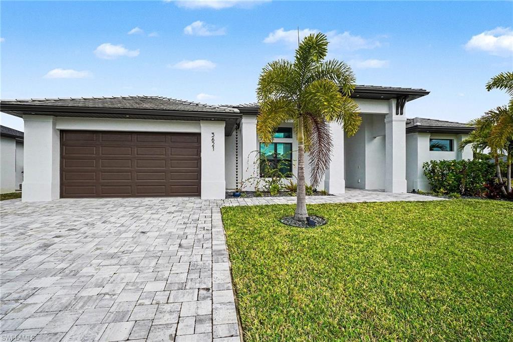Image 2: Prairie-style home with a front lawn, an attached garage, decorative driveway, and stucco siding