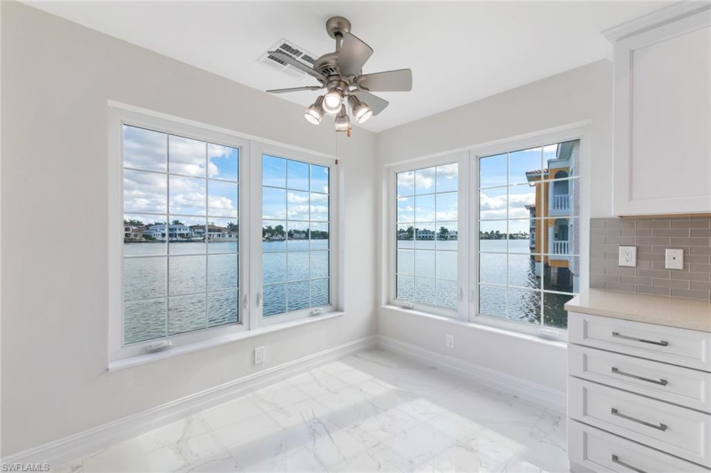 Image 4: Unfurnished dining area with a water view, light marble finish floors, and a ceiling fan