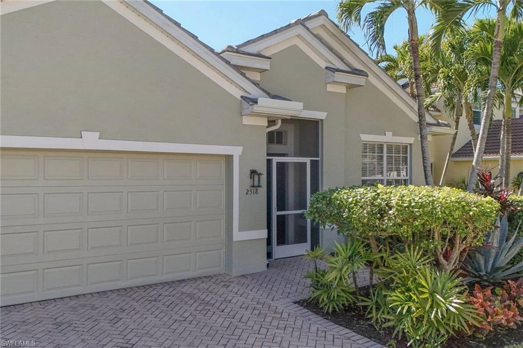 Image 3: View of front facade with stucco siding and decorative driveway