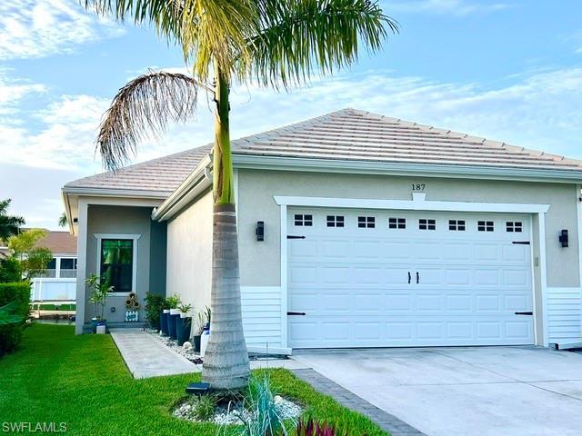 Image 1: Stucco exterior with a tile roof, an integrated two-car garage, a concrete driveway, and a concrete walkway to the entry