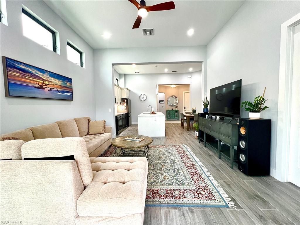 Image 3: Spacious living area featuring high ceilings, wood-finish flooring, recessed lighting, a ceiling fan, and transom windows