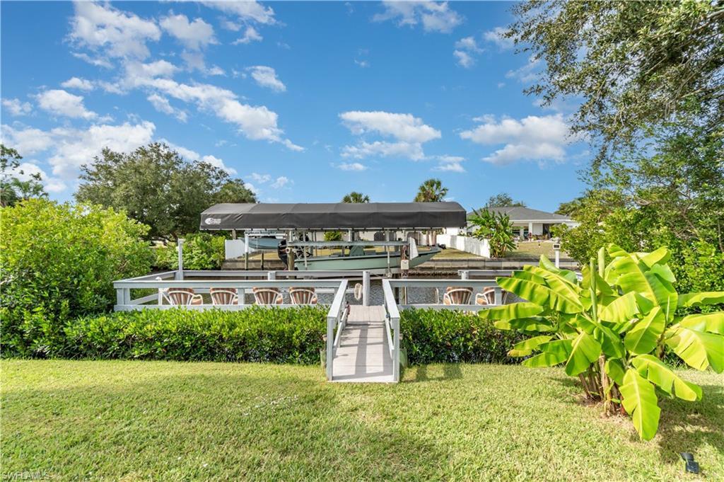 Image 4: View of home's community with boat lift, a dock, and a yard