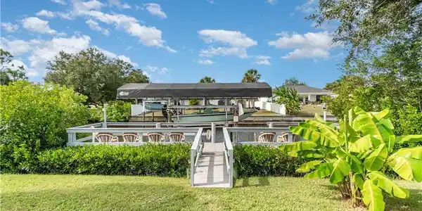 Image 4: View of home's community with boat lift, a dock, and a yard