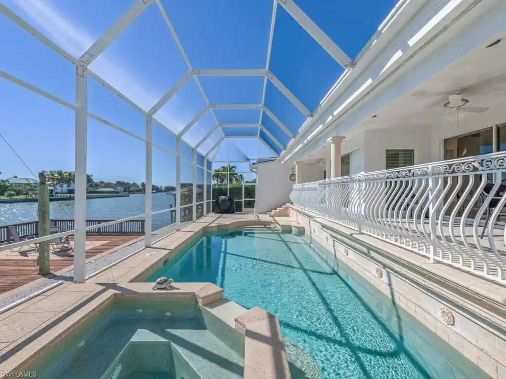 Image 1: View of pool with a sunroom, a lanai, a patio area, a water view, and a pool with connected hot tub