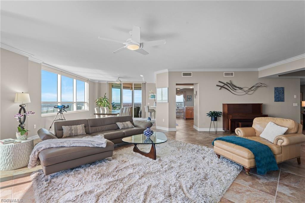 Image 1: Living room with a ceiling fan, a water view, light tile patterned floors, and a wall of windows