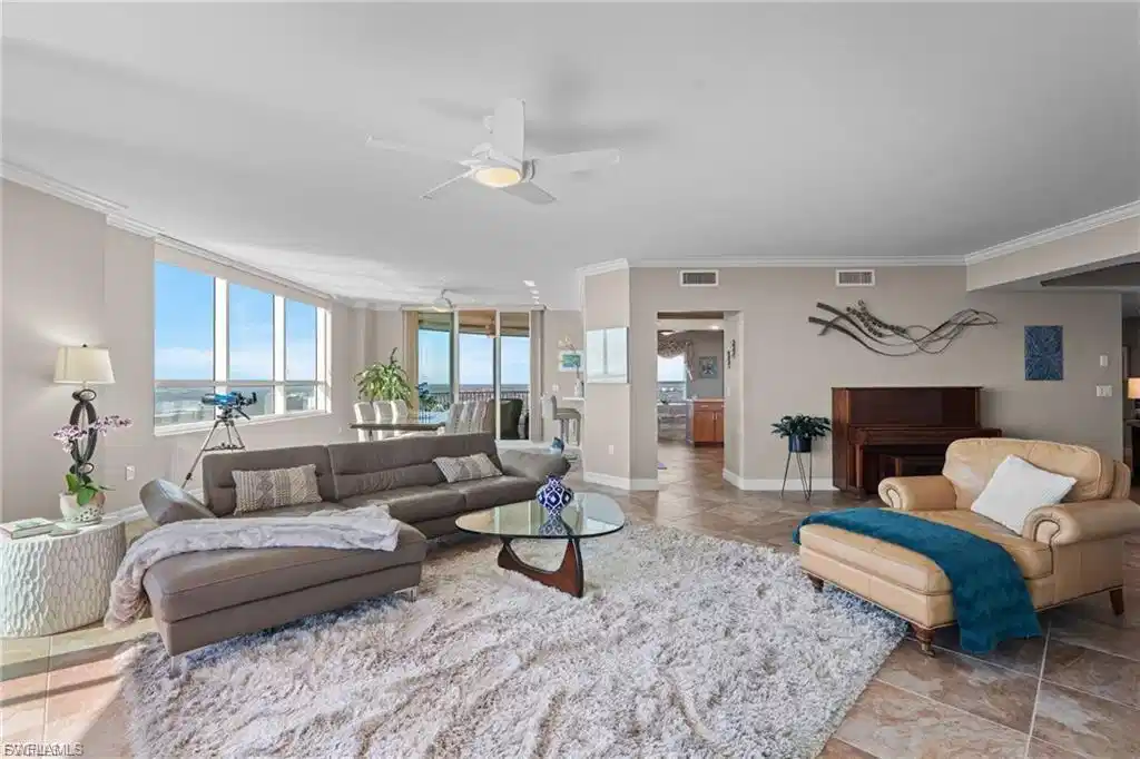 Image 1: Living room with a ceiling fan, a water view, light tile patterned floors, and a wall of windows