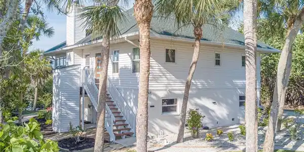 Image 4: View of side of home featuring NEW stairs, NEW door, NEW landscaping, elevator for small items/groceries, IMPACT windows