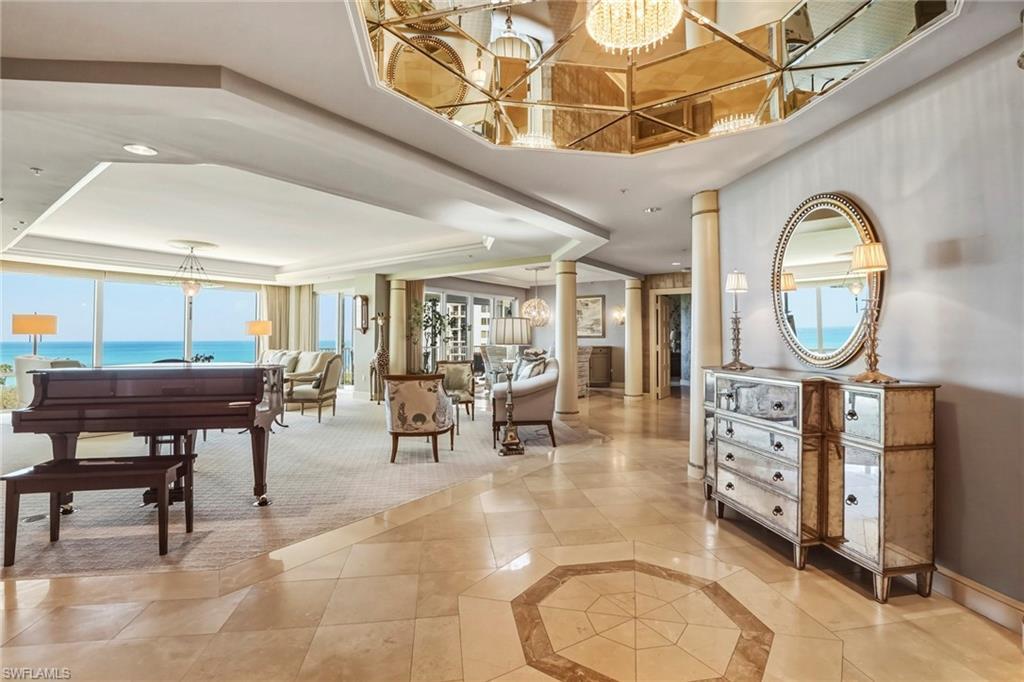 Image 3: Foyer entrance with a chandelier, decorative columns, a raised ceiling, light tile patterned floors, and inlaid floor details