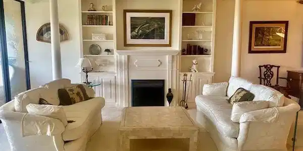 Image 4: Living room with crown molding, built in features, light colored carpet, and decorative columns
