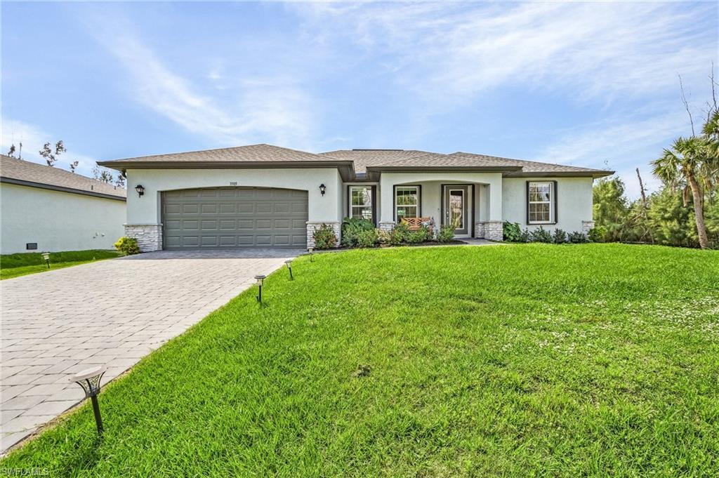 Image 2: Florida-style home with stucco siding, stone siding, a front lawn, and decorative driveway