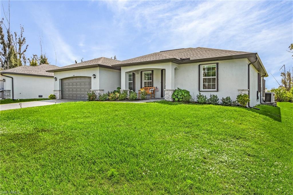 Image 3: View of front of property with stucco siding, a front lawn, driveway, and a garage