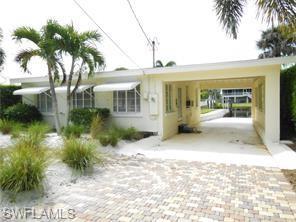 Image 2: View of front of property with driveway and a carport