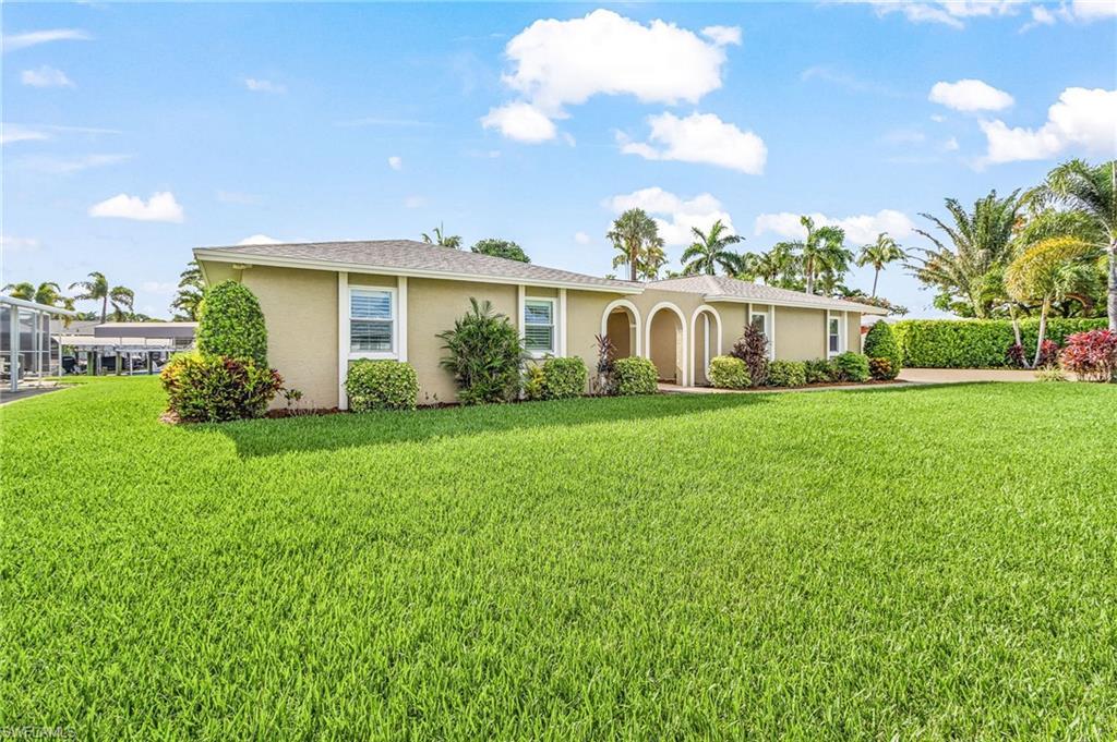 Image 3: Expansive green lawn with a single-story residence featuring a tan exterior, multiple windows, and an arched entry