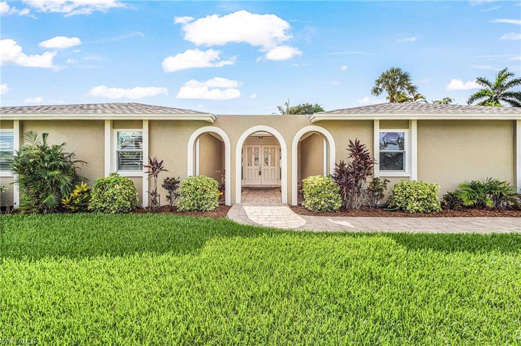 Image 4: Stucco exterior featuring an arched entryway with decorative double doors