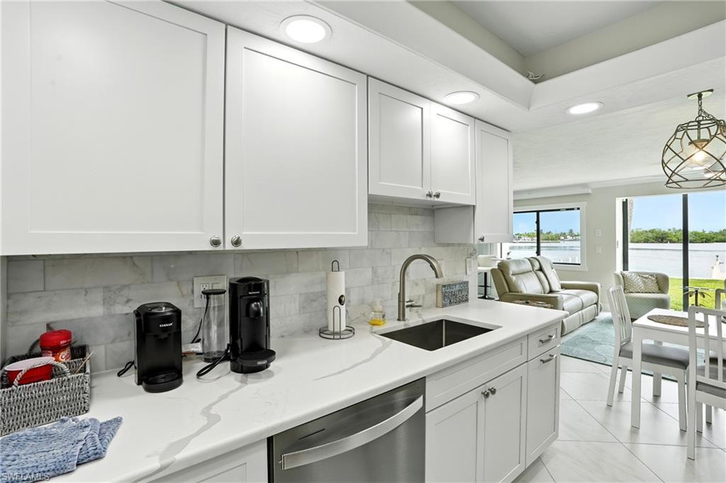 Image 3: Kitchen with recessed lighting, white cabinets, tasteful backsplash, stainless steel dishwasher, and light tile patterned floors