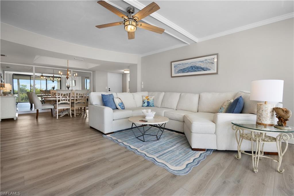 Image 3: Open-concept living area featuring wood-finish flooring, a ceiling fan with integrated lighting, and a dining area with a chandelier