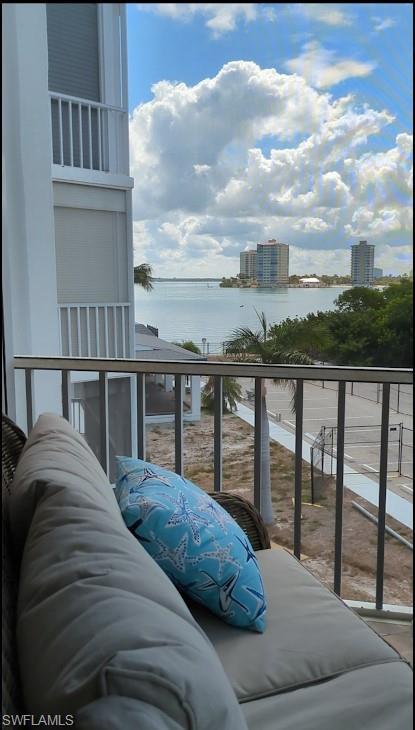 Image 4: Balcony featuring water scenery with distant buildings and lush foliage