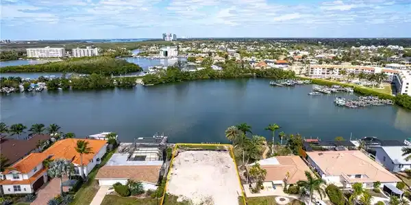 Image 2: Aerial overview of property's location featuring a nearby body of water, property boundaries highlighted, and a marina