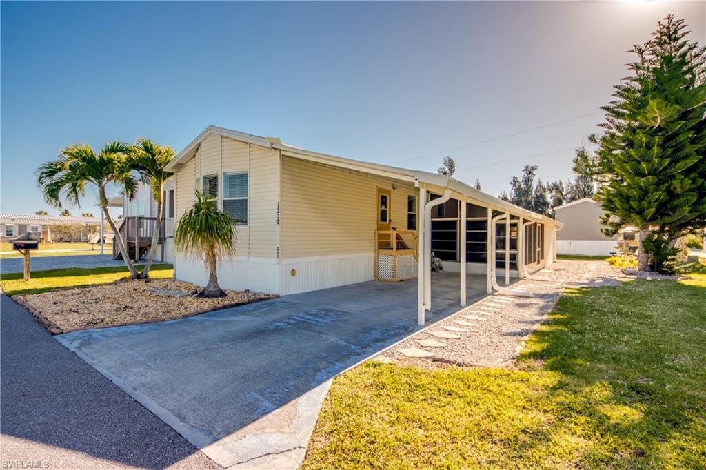 Image 1: The property features a concrete driveway, a screened-in porch, and a landscaped yard with mature trees and palm trees