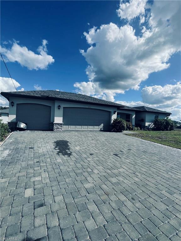Image 2: View of front of property with decorative driveway and an attached garage