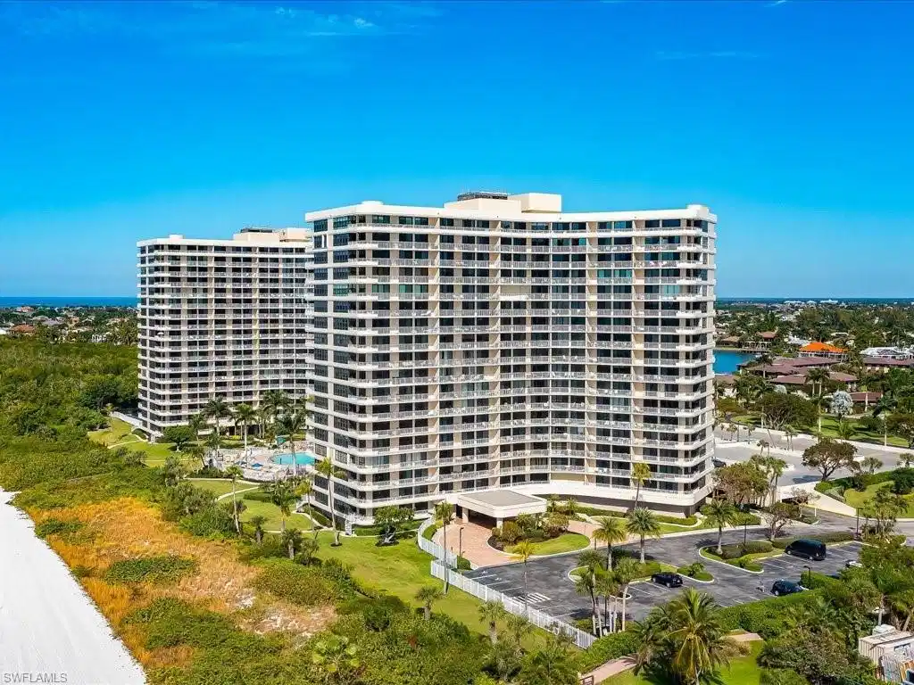 Image 1: Twin high-rise buildings featuring multiple balconies, a ground-level swimming pool, and extensive landscaping with palm trees