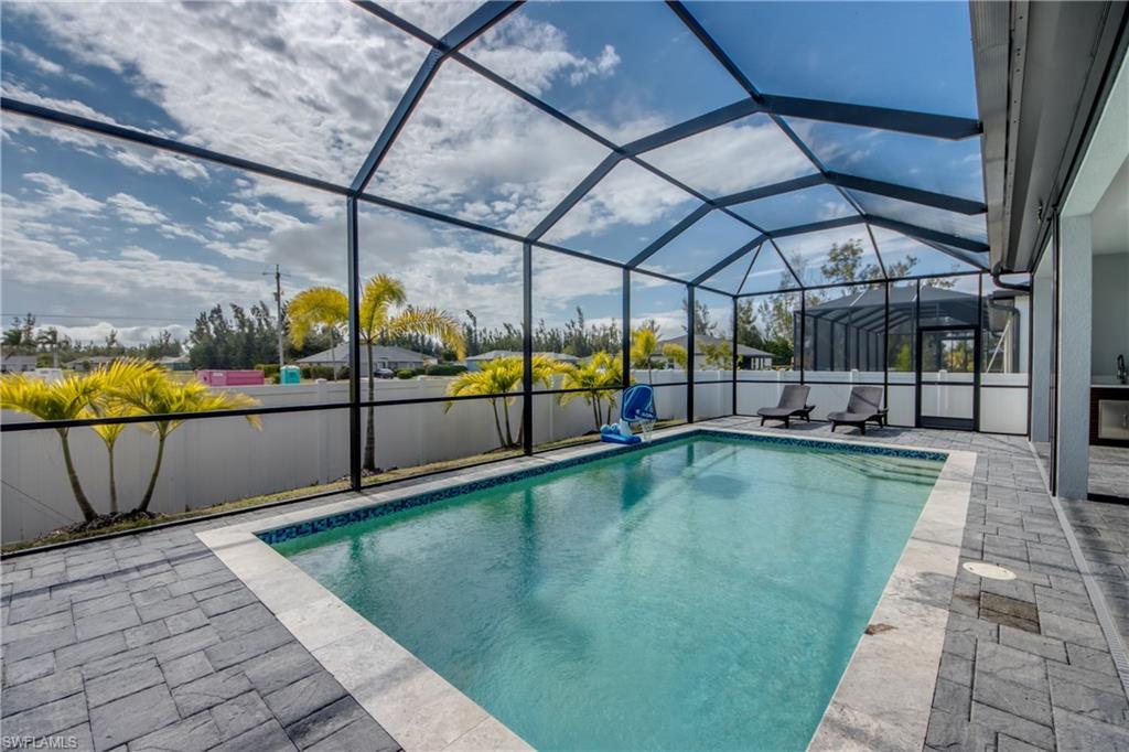 Image 4: View of swimming pool featuring a sunroom, glass enclosure, a fenced backyard, and a patio
