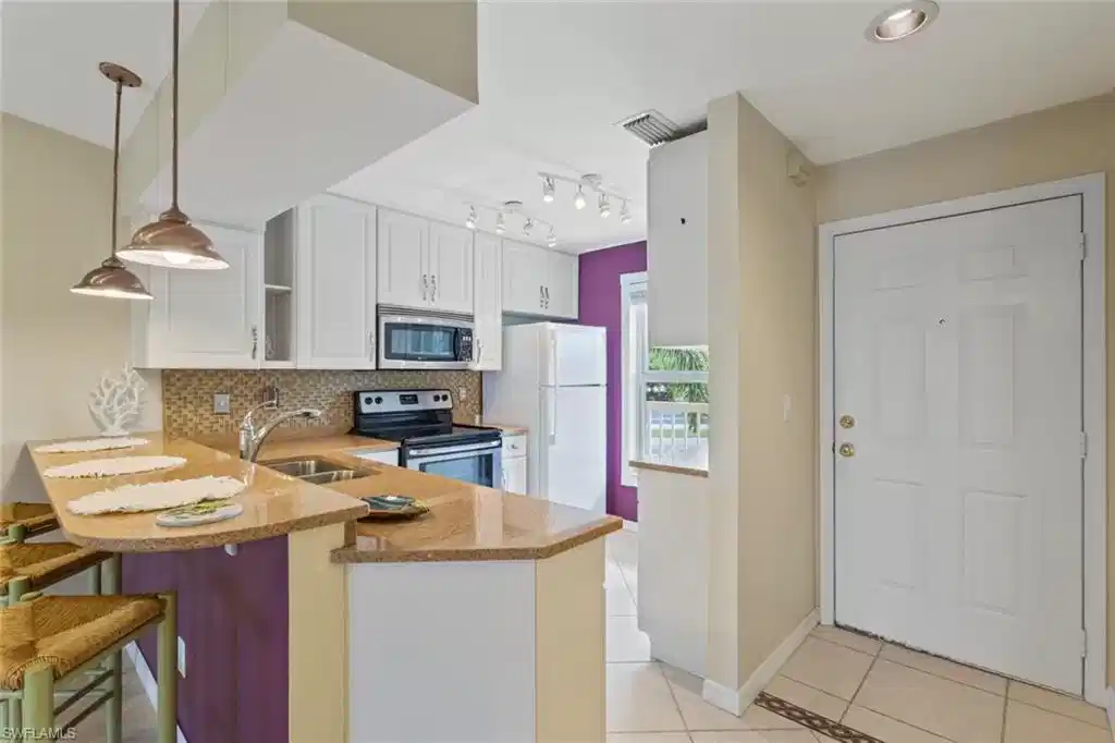 Image 1: Kitchen featuring light tile patterned flooring, decorative backsplash, a peninsula, appliances with stainless steel finishes, and light stone counters