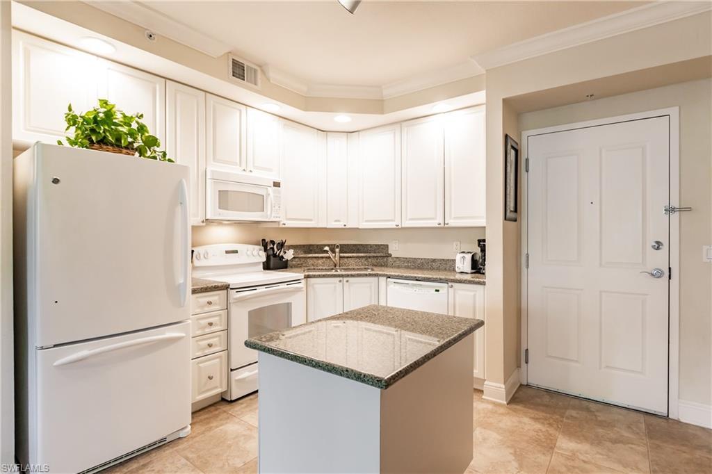 Image 4: Kitchen featuring white appliances, ornamental molding, stone countertops, white cabinets, and a center island