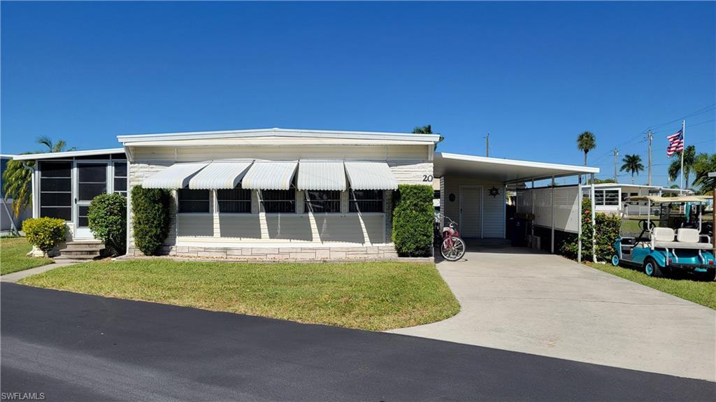 Image 1: Manufactured / mobile home with a front yard, a carport, driveway, and a sunroom