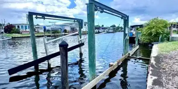 Image 4: Waterfront property featuring a boat lift with wooden pilings and a concrete seawall