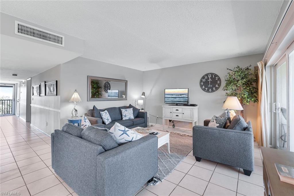 Image 4: Living room with light tile patterned floors and a textured ceiling