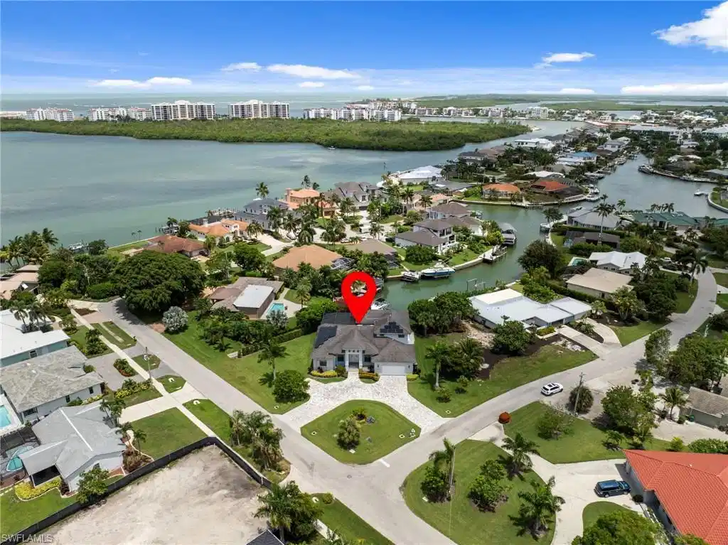 Image 1: Waterfront property featuring a private boat dock, lush tropical landscaping, and a paver driveway