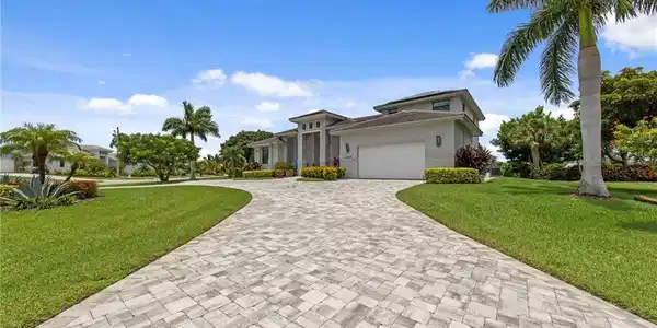 Image 2: Circular paver driveway leading to a contemporary residence with a two-car garage