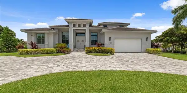 Image 3: Contemporary exterior with a prominent portico entry, a paver driveway, an integrated garage, and manicured landscaping
