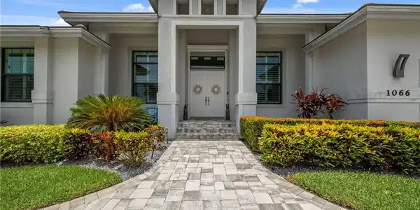 Image 4: Contemporary stucco exterior with a prominent portico entry and double doors