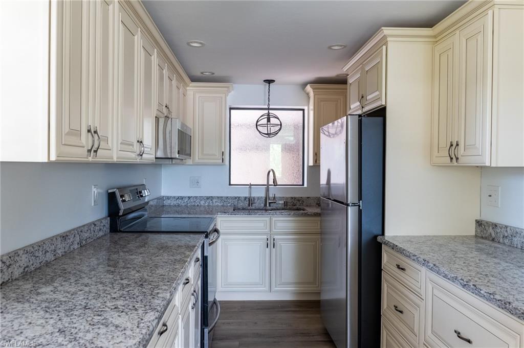 Image 2: Kitchen featuring recessed lighting, stainless steel appliances, a sink, light stone countertops, and pendant lighting
