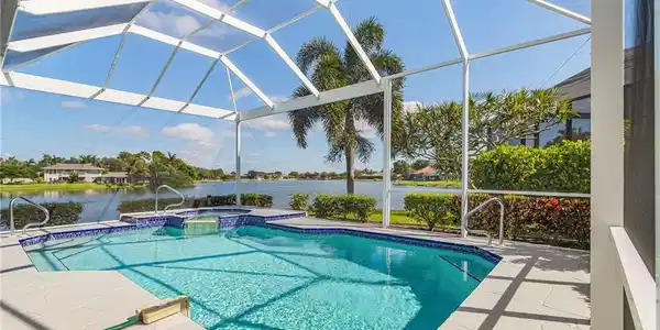 Image 3: Screened enclosure featuring a swimming pool, integrated spa, and expansive water frontage