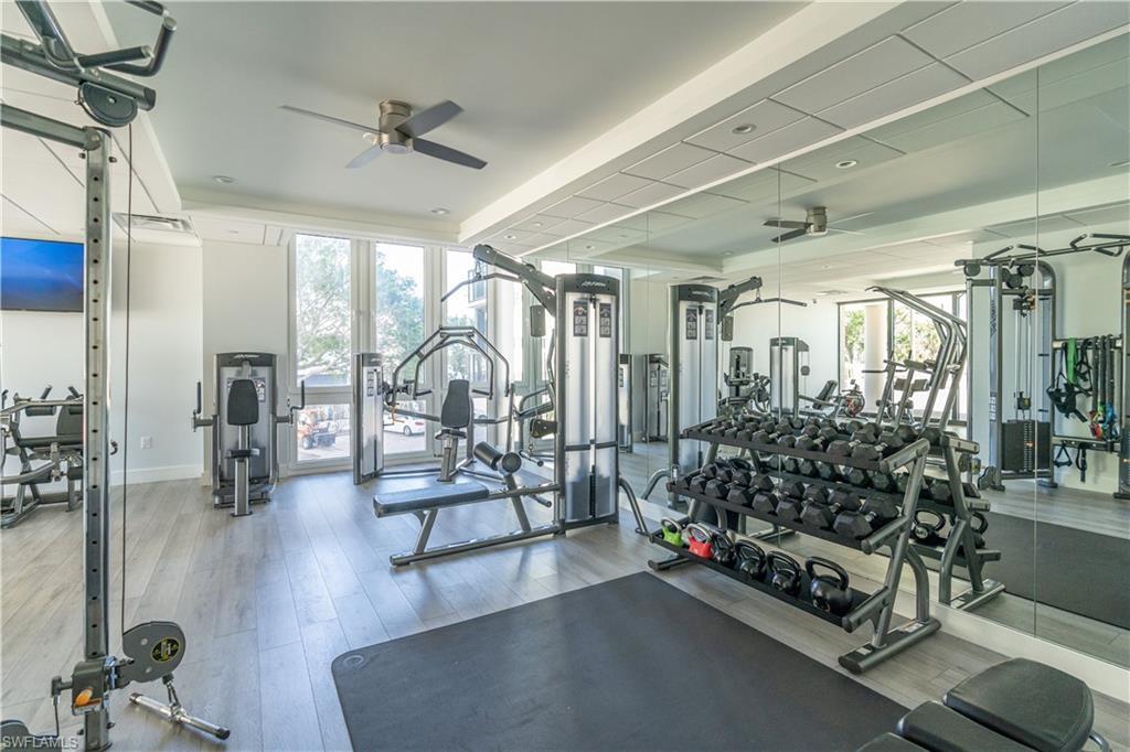 Image 4: Exercise room with hardwood / wood-style floors, ceiling fan, and a raised ceiling