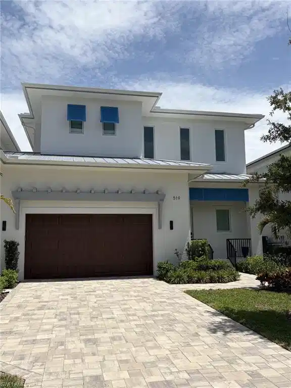 Image 1: Modern two-story residence featuring a white stucco exterior and a metal roof