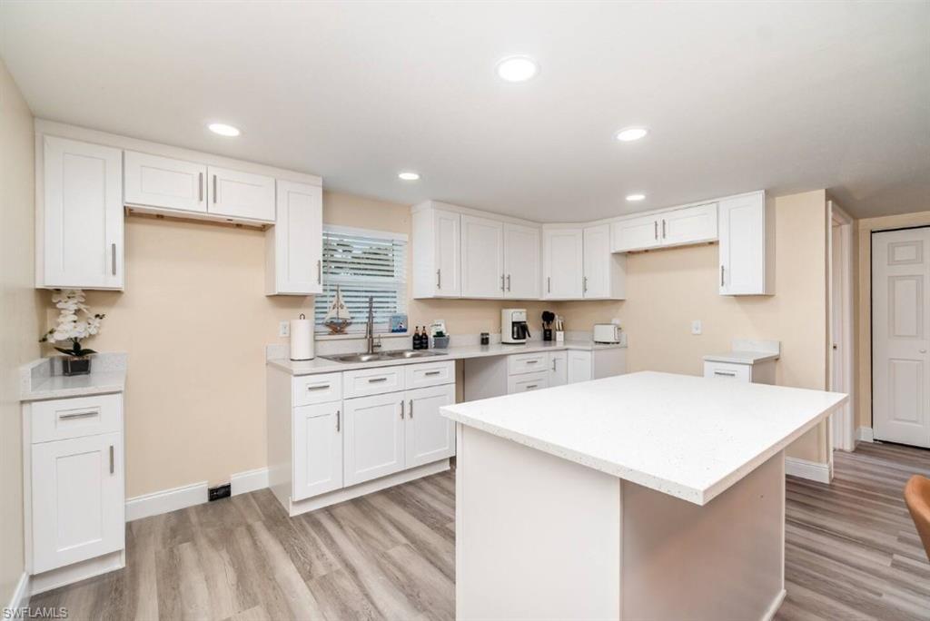 Image 4: Kitchen featuring white cabinetry, a center island, light wood finished floors, recessed lighting, and light countertops
