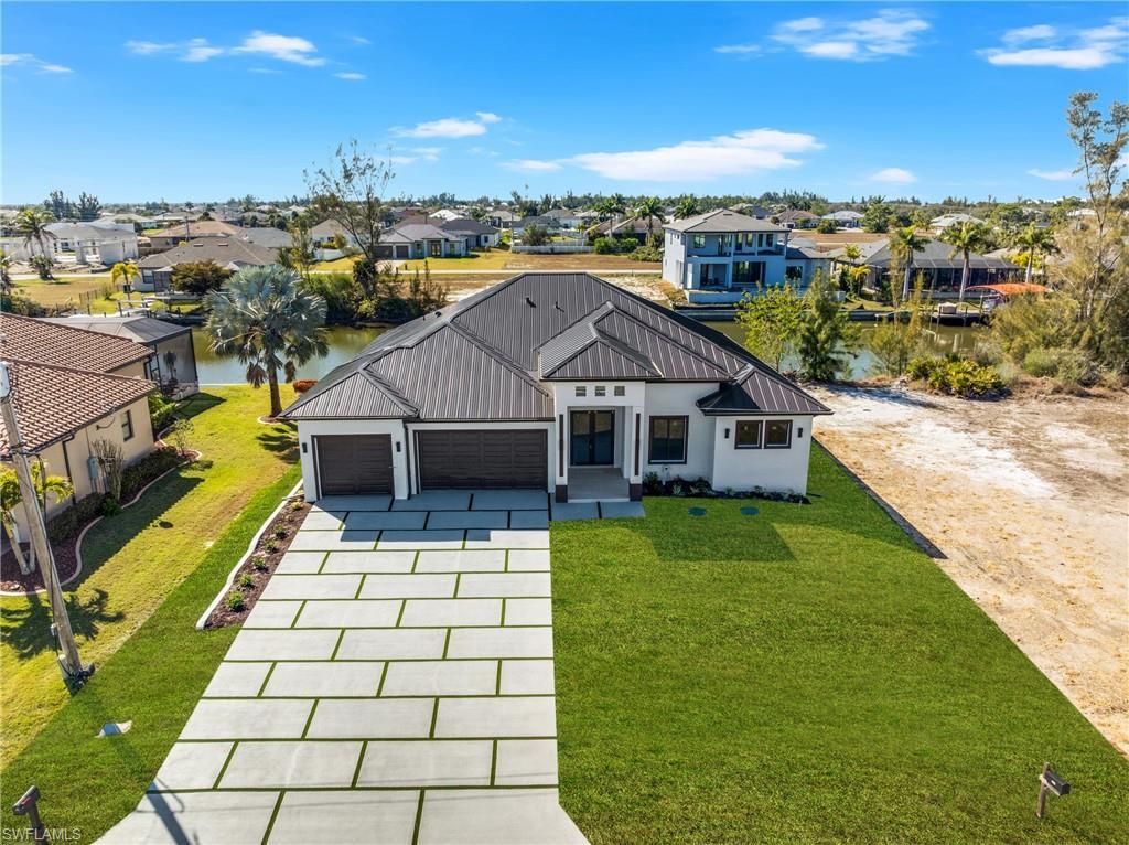 Image 3: Modern farmhouse with a garage, concrete driveway, a front yard, stucco siding, and a metal roof