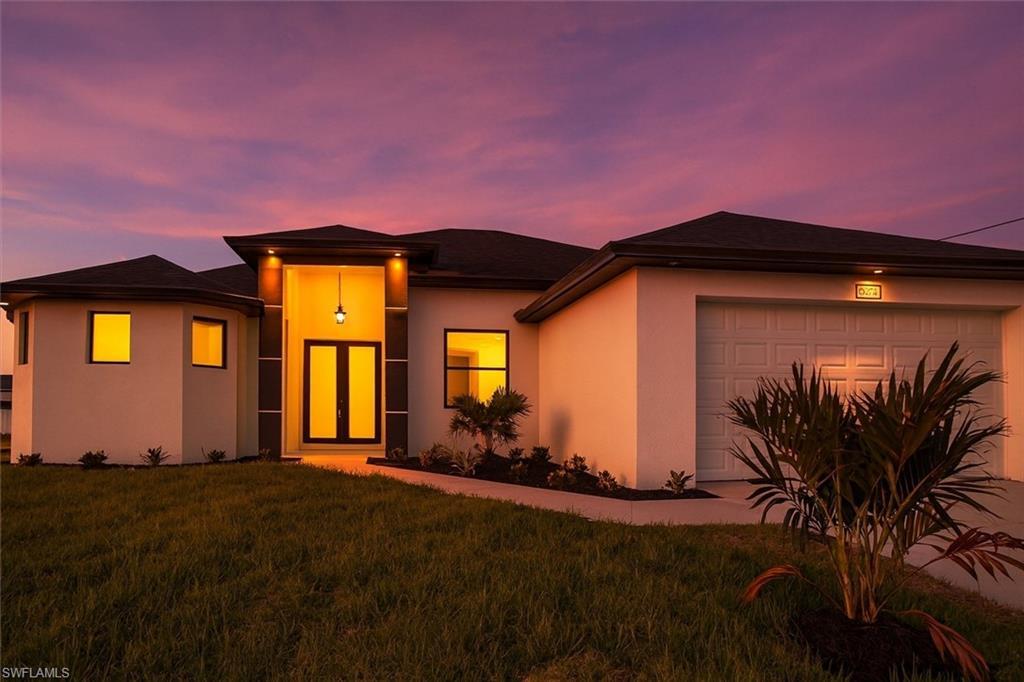 Image 1: Coastal Modern home featuring a front yard, stucco siding, and a garage