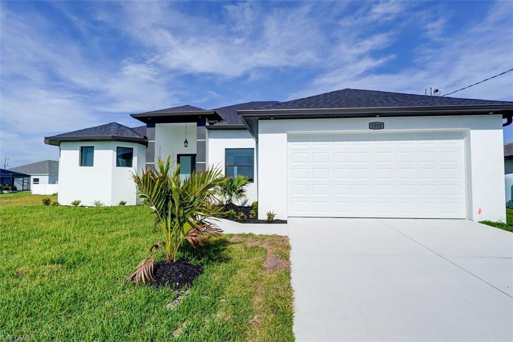 Image 2: Coastal modern house featuring stucco siding, concrete driveway, an attached garage, and a front yard
