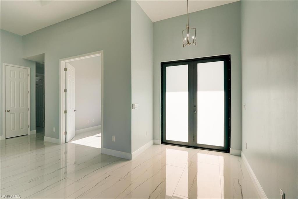 Image 4: Entrance foyer with healthy amount of natural light, a towering ceiling, french doors, a chandelier, and light marble finish floors
