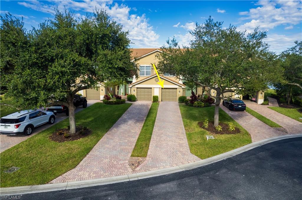 Image 2: Townhome exterior featuring a stucco facade, attached two-car garage, paver driveway, and mature trees