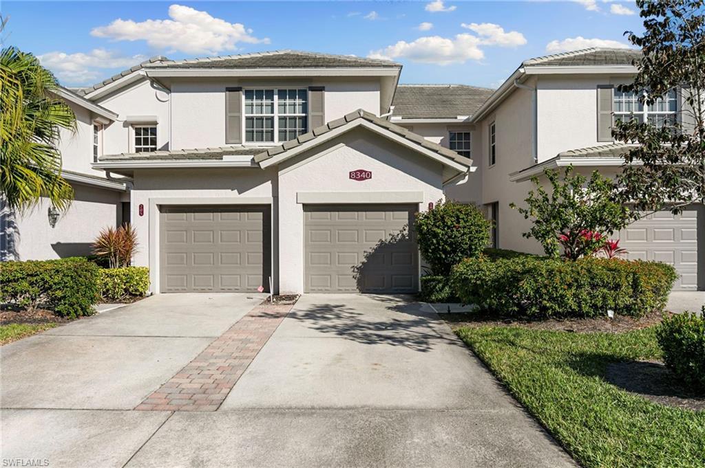 Image 1: Traditional-style house featuring driveway, a garage, stucco siding, and a tiled roof